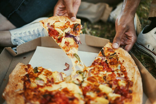 Pizza, food and hands of a couple eating in a park, picnic and relax on an outdoor date together. Hungry, fast food and zoom of man and woman with lunch or dinner in nature for peace and calm.