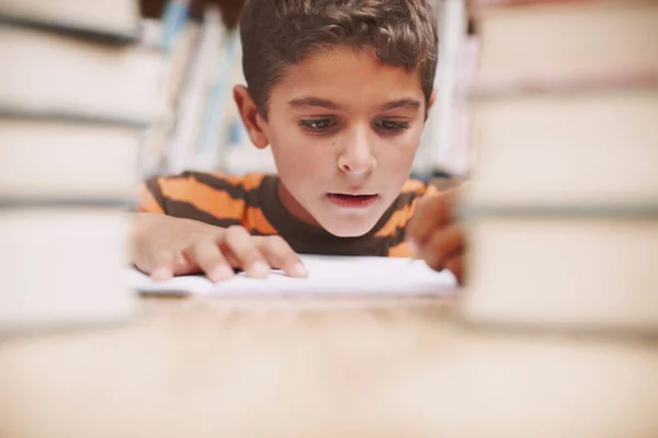 他喜欢讲故事 一个可爱的小男孩在图书馆边读书边做功课 — 图库照片