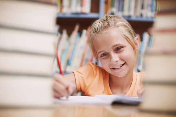 她很喜欢她的学业 一个快乐的小女孩在图书馆边读书边做功课 — 图库照片