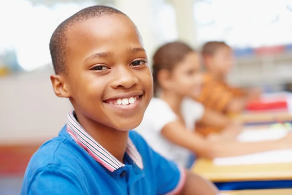 Inspired children become top achievers. Confident young african-american boy smiling at you in his class - copyspace