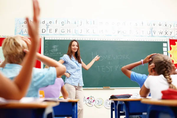 宿題はあなたのテストになります 教室の黒板の先生に立っている美しい若い先生 — ストック写真
