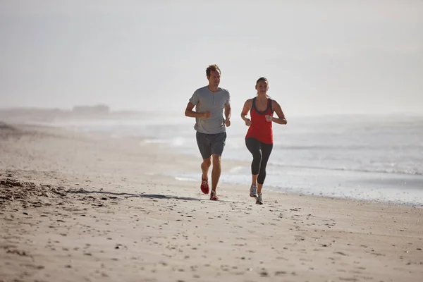 An early morning jog on the beach. a young couple exercising outdoors