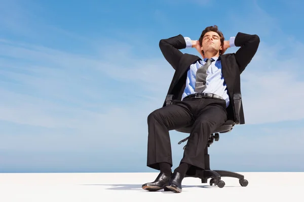 成功的商人坐在办公椅上休息 成功的商人在晴朗的天空下坐在办公椅上休息 — 图库照片