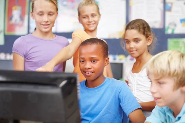 友達とインターネットを楽しむ クラスの間にコンピュータの周りに座って立っている若い子供たちのグループ — ストック写真