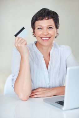 İnternetten alışveriş. Bilgisayarı kullanırken kredi kartı tutan mutlu bir iş kadını.