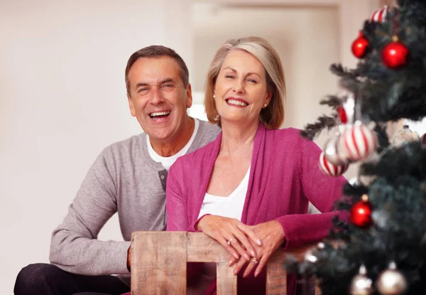 一对快乐而成熟的夫妇坐在自家的圣诞树旁 一对快乐而成熟的夫妇坐在自家圣诞树旁的画像 — 图库照片