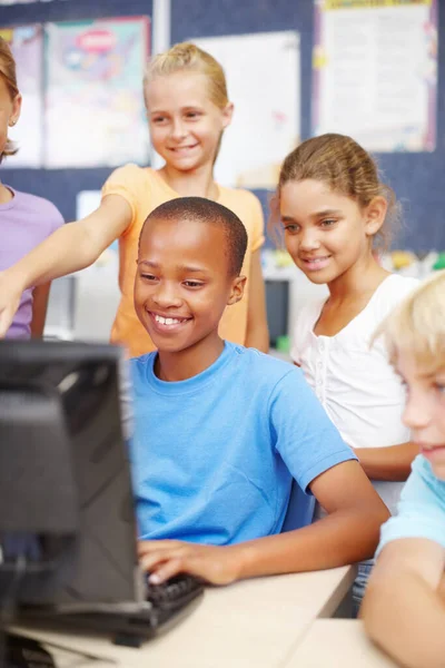 友達とコンピュータゲームをプレイ クラス中にコンピュータの周りに座って立っている多民族の子供たちのグループ — ストック写真