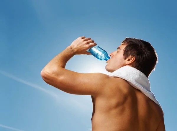 年轻的男子在锻炼后喝水 一个赤身裸体的男人在清澈的天空下运动后喝水的画像 — 图库照片