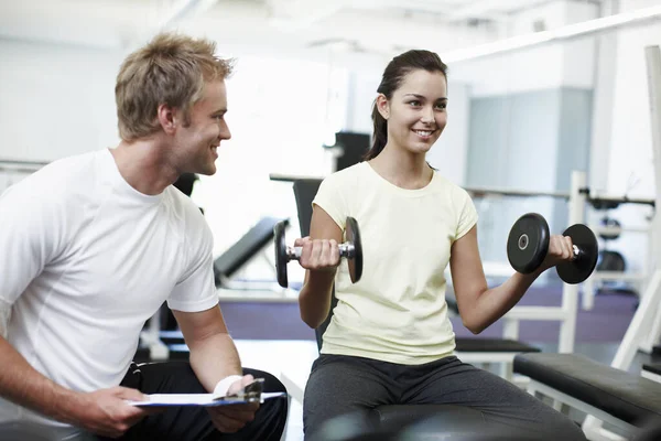 Youre doing a great job so far. an attractive young woman weight training with her personal trainer
