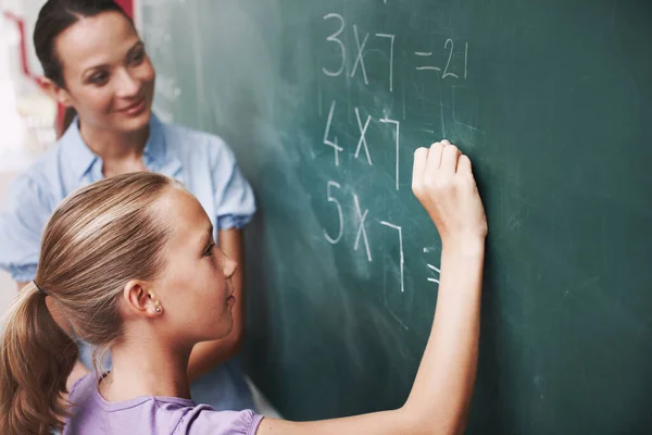 迷你数学家 老师微笑着看着一个在黑板上做数学的小女孩 — 图库照片