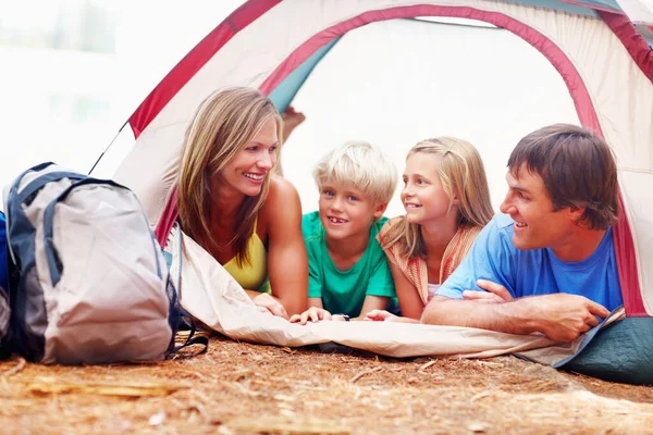 Family in tent. Portrait of family of four relaxing in tent on a camping holiday