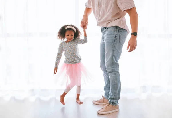 Family, love and father dance with girl, having fun and bonding in home. Smile, happy and parent with child or kid holding hands, playing and dancing, care or enjoying quality time together in house.