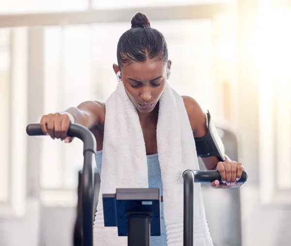 Stationary, bike and fitness black woman in gym for exercise challenge, workout motivation and goal with speed, fast and heart algorithm technology. Cycling machine, sports and Crossfit training girl.