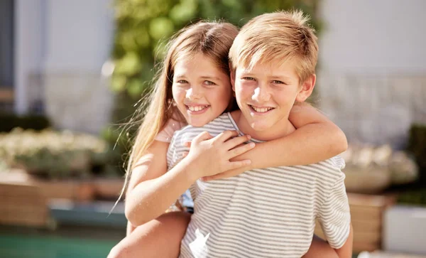 Children, hug and love, piggy back and happy in portrait together, young kids outdoor and family bonding in backyard. Brother and sister smile, relationship and care, spending quality time in nature.