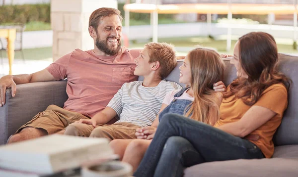 Happy family, sofa and relax together, laugh and funny joke with smile, happiness and sitting in home. Father, mother and young kids on couch with bonding, comic and love in lounge at holiday house.