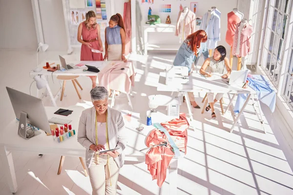 Fashion workshop, diversity or women working with tablet, fabric or design research for creative clothing strategy. Collaboration, teamwork or designer woman in workshop or manufacturing factory.