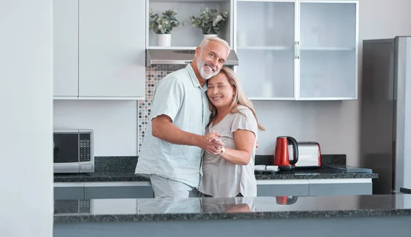 stock image Love, marriage and dance with a senior couple in the kitchen of their home together for bonding or romance. Portrait, happy and smile with a mature man and woman romantic dancing in their house.