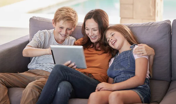 Relax, happy and tablet with mother and children on sofa for streaming, internet and social media app. Smile, subscription and movies with mom and kids in living room for family home for cartoon.
