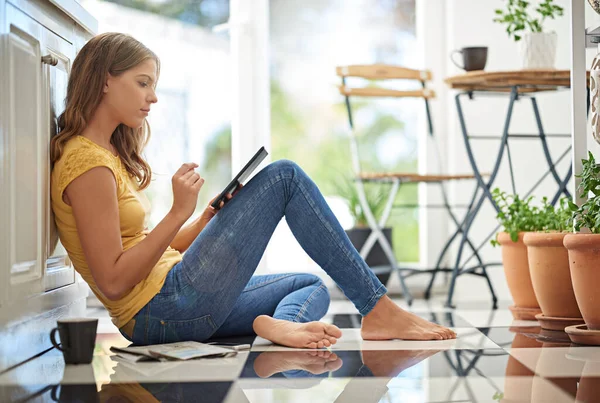 Stock image Relaxing in the kitchen. an attractive young woman chilling on her kitchen floor