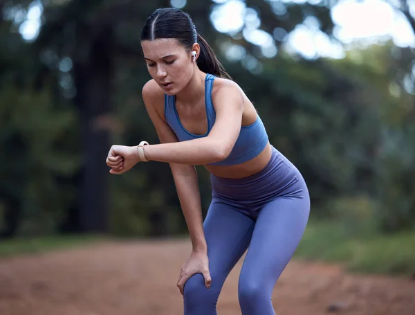 Woman, earphones or fitness smart watch check in nature exercise, sustainability environment workout or forest trail training. Runner, sports athlete or person with clock time or health radio podcast.