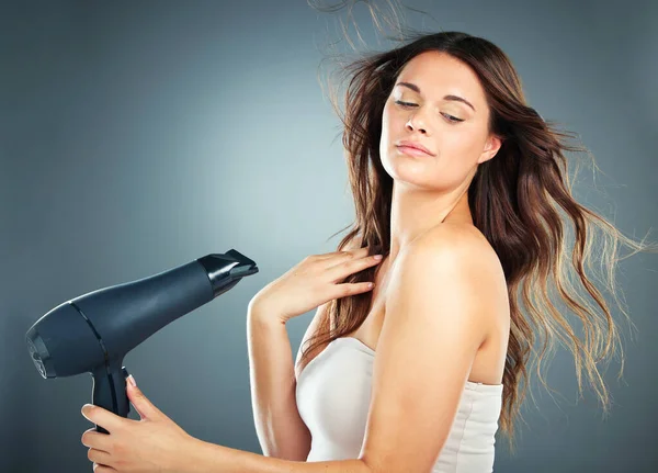 stock image Hair care, beauty and woman in studio with a hairdryer for salon or hairdresser mockup with cosmetics, makeup and growth shampoo product. Aesthetic model with styling tool for self care and wellness.