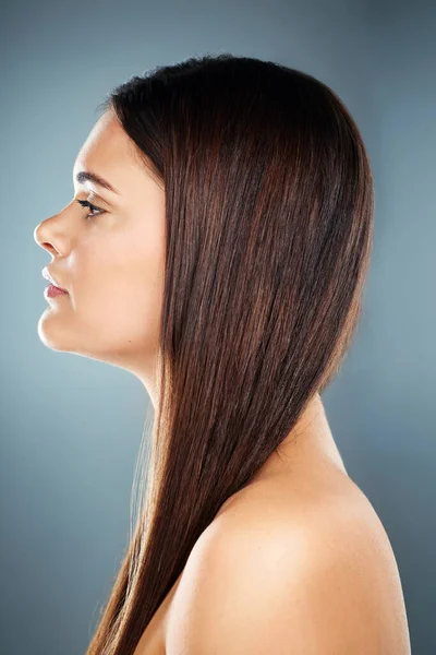Hair care, brunette and side profile of a woman with salon straight hair against a blue studio background. Wellness, beauty and face of a model with shine, clean and healthy hair with a backdrop.