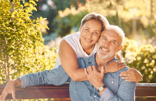 Nature, bench and portrait of a senior couple relaxing in an outdoor green garden together. Happy, smile and elderly man and woman in retirement embracing, bonding and sitting in a park in Australia
