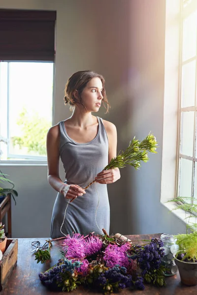 Dont quit your daydream. a beautiful woman completing a floral bouquet on a wooden counter top
