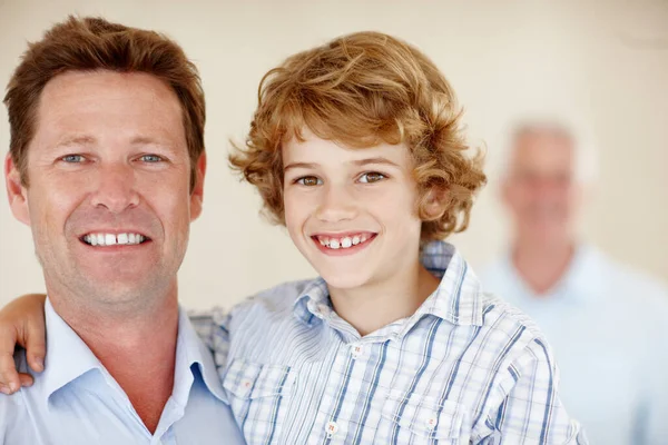 他是他父亲的儿子 一个小男孩和他的父亲的肖像画 背景是爷爷 — 图库照片