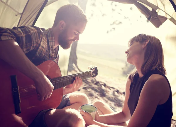 屋外で音楽を作る 若い男がテントの中で彼女にギターを弾いていて — ストック写真