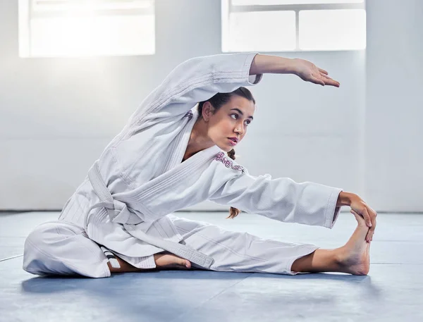 Martial arts, karate or woman stretching before training practice, fitness workout or challenge competition. Girl, warrior or taekwondo fighter warm up for dojo self defense or safety security lesson.