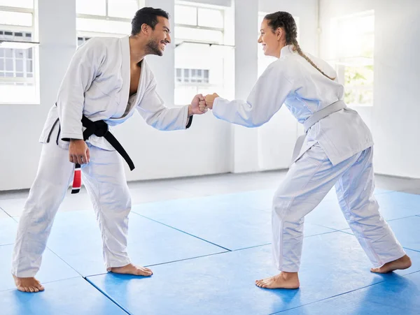 Fist bump, support and couple in karate, training and teaching in partnership for motivation in self defense. Goal, fight and man and woman with unity in taekwondo for exercise and fitness at a club.