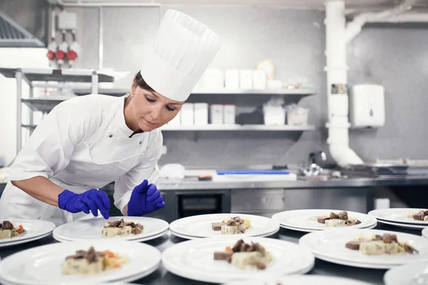 From her hands to you table. a chef plating food for a meal service in a professional kitchen