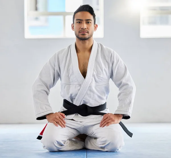 Portrait, karate and sensei with a sports man kneeling on the gym floor of a dojo or fitness club for self defense. Training, workout and fight with a martial arts professional in a sport facility.