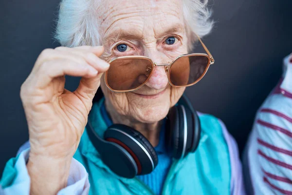 音楽ヘッドフォン 高級シニアスタイルや創造的なアクセサリーを持つ老婦人のメガネ クールなファッションの肖像画 デザイナーブランドのサングラスを持つ高齢者退職者のビジョン 健康と顔 — ストック写真