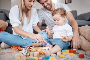 Aile, oyuncaklar ve oyun, ebeveynler ve çocuklarla birlikte oturma odasında oynaşma ve bağ kurma. Büyüme, çocukluk oyuncağı ve mutlu aileyle aşk, çocuklu anne ve baba ve rahatlama.
