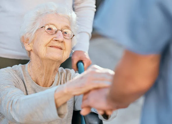 stock image Holding hands, caregiver and senior woman in wheelchair for support outdoor in retirement home. Love, trust and healthcare nurse or medical wellness doctor for disability patient with kindness.