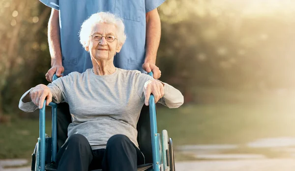 Healthcare, portrait and old woman in wheelchair with nurse in nature for wellness. Outdoors, disability and retired female with medical worker for healthy sunshine or enjoying time at park or garden.
