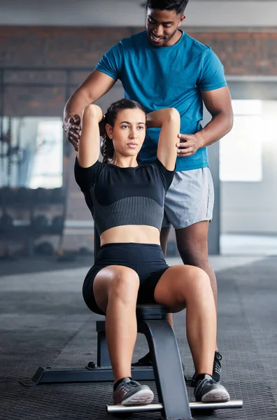 Training, weights and woman with a personal trainer for help during exercise, fitness and motivation in the gym. Health, strong and girl athlete with a coach helping with a workout at a club.