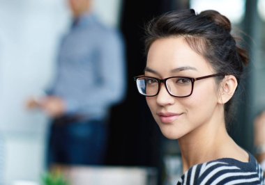 She exudes career confidence. Portrait of an attractive young woman sitting in an office with colleagues in the background clipart