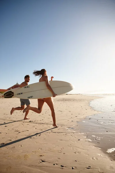 夏のサーフィンが待っています サーフボードを持って海岸沿いを走っている若いサーフィンカップルは — ストック写真
