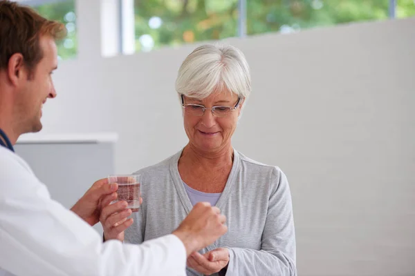 Feel better with modern medicine. a doctor handing some medication over to a senior patient