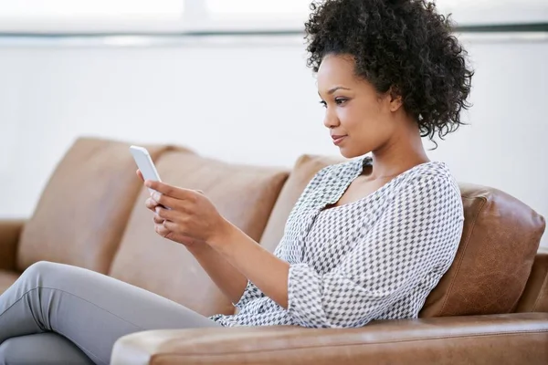 Terhubung Sofa Seorang Wanita Yang Menarik Menggunakan Smartphone Nya Saat — Stok Foto