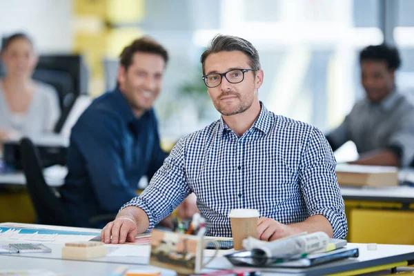 stock image Behind every good manager is a great team. Portrait of an office worker sitting at his desk with colleagues in the background