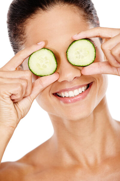 Fresh Beauty. A smiling woman holding cucumber slices up to her eyes
