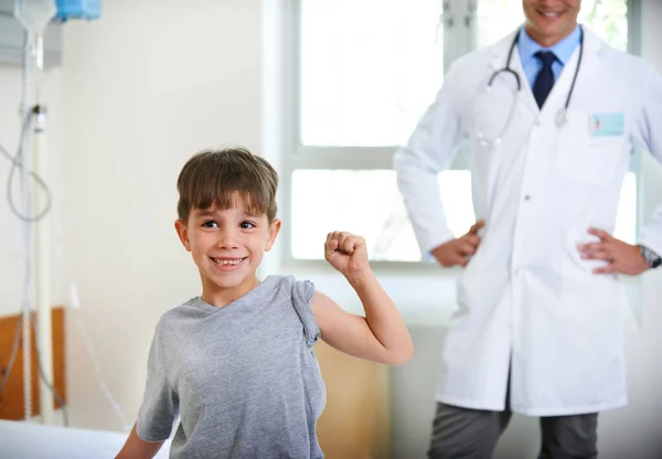 最坚强的病人的第一名 一个可爱的小男孩在医院里扭动着胳膊肌肉 — 图库照片