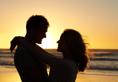 Beni tamamlıyorsun. Gün batımında sahilde birbirine bakan bir çiftin romantik görüntüleri.