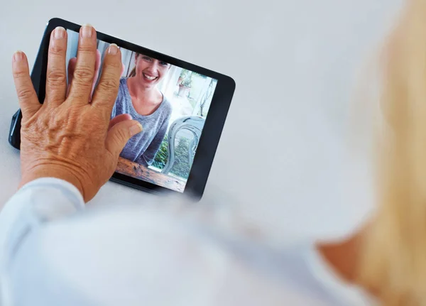 stock image Distance made bearable. Rearview of a senior woman touching her digital tablet while having a video conference with her grandchild