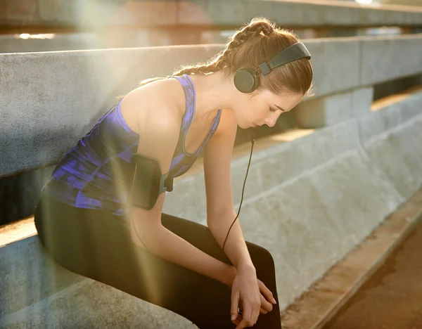 stock image Getting mentally focused for her run. a young female jogger listening to music before a run through the city