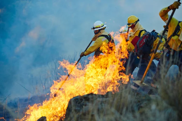 炎の上で 野火と戦う消防士 — ストック写真